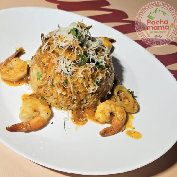 Peruvian shrimp and rice dish, topped with cheese and herbs, on a white plate.
