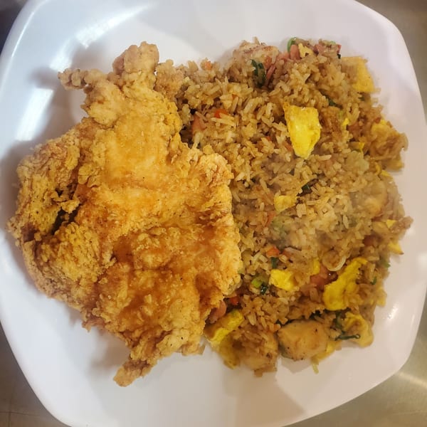 Crispy fried chicken cutlet and Peruvian fried rice with scrambled egg and vegetables on a white plate.