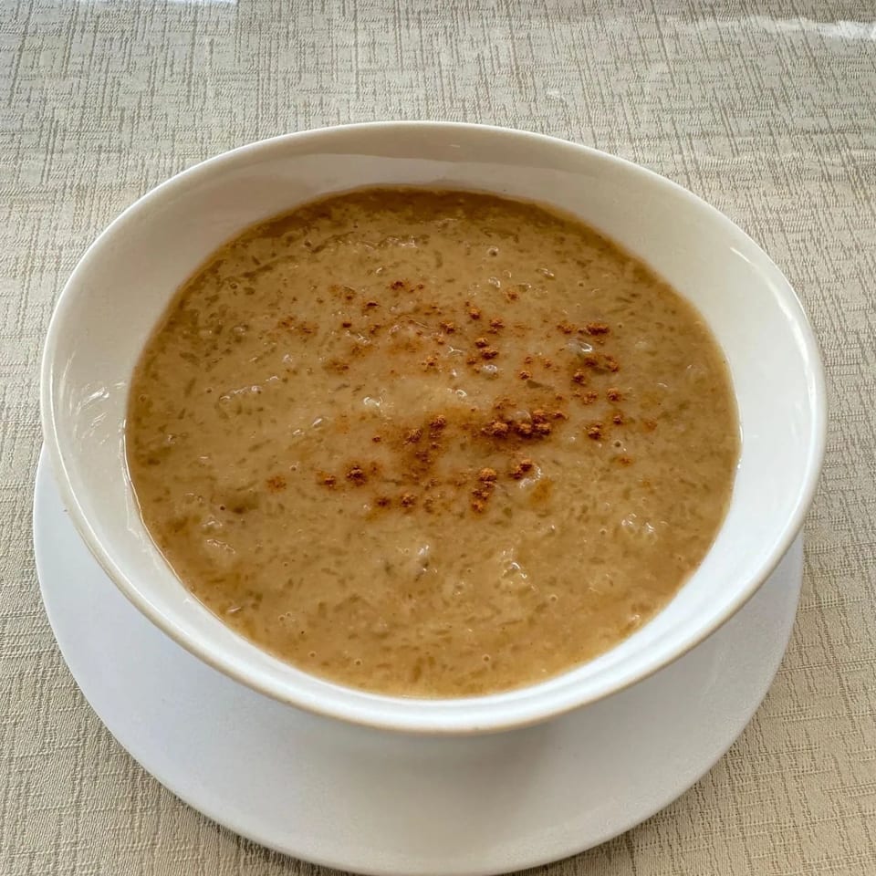 A Peruvian arroz con leche dessert, a creamy rice pudding topped with cinnamon, in a white bowl.