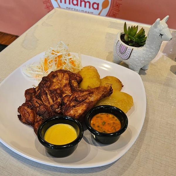 Peruvian roasted chicken with golden potatoes, shredded cabbage, and two dipping sauces on a white plate.