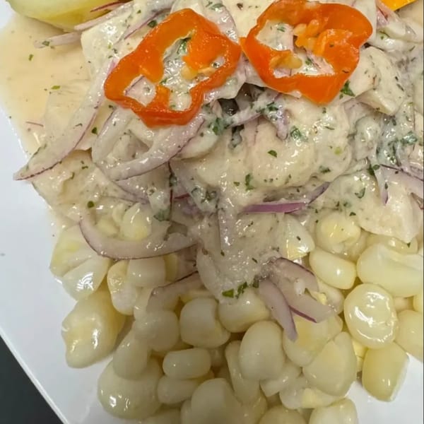 Peruvian ceviche with white fish, red onions, orange peppers, and large white corn kernels.