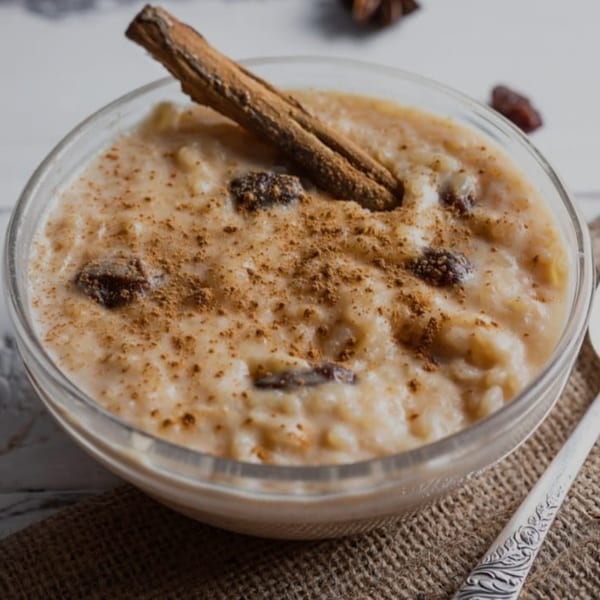 Peruvian arroz con leche dessert in a glass bowl, topped with cinnamon and raisins.